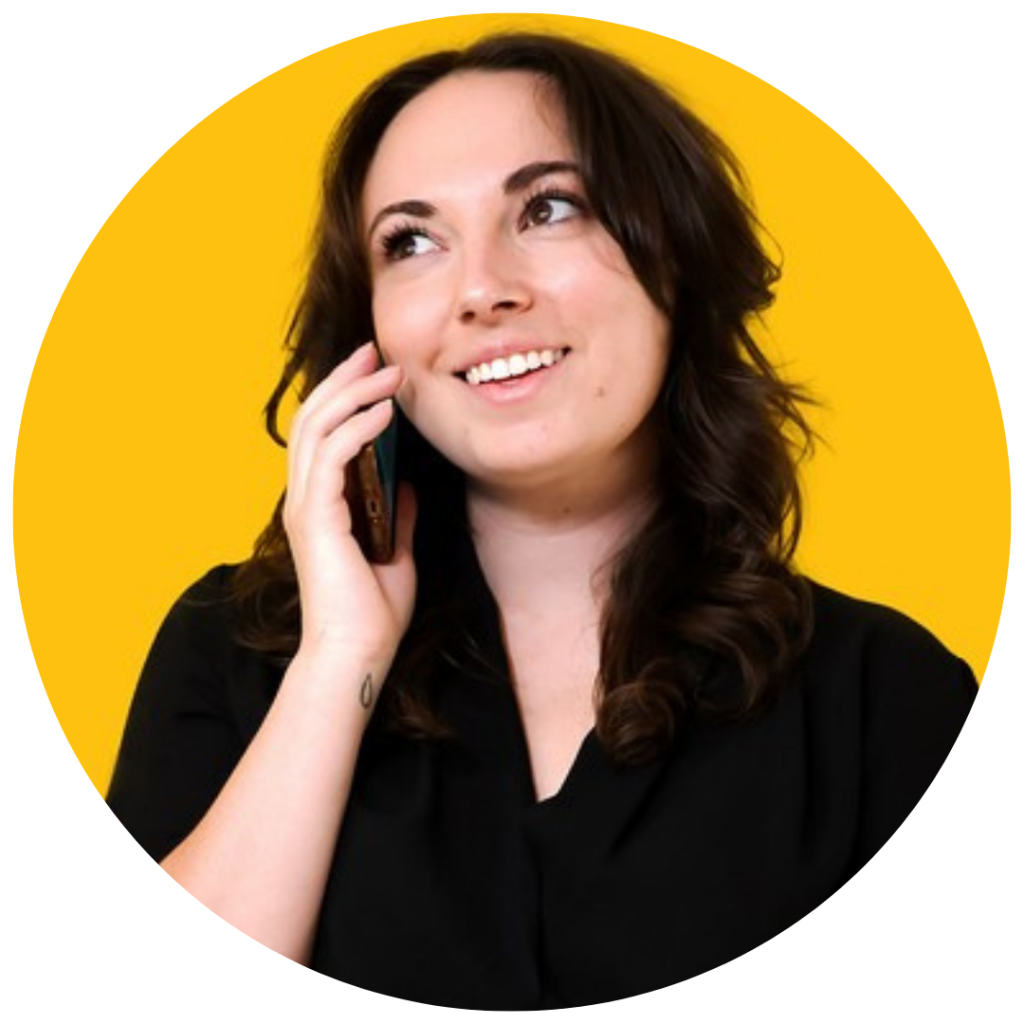 A picture of Mandy holding a phone to her ear. She is smiling and looking upwards.